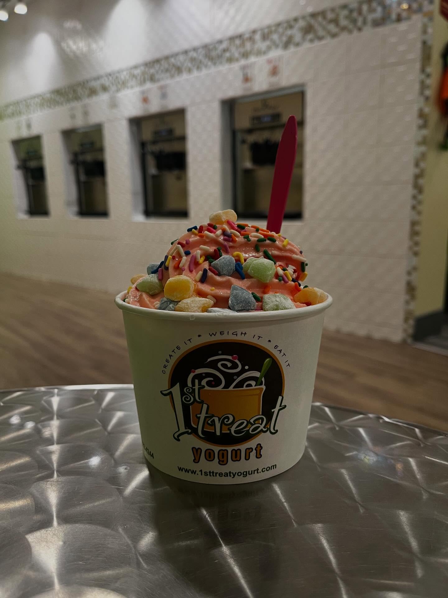 A cup of 1st Treat strawberry frozen yogurt topped with sprinkles and mochi